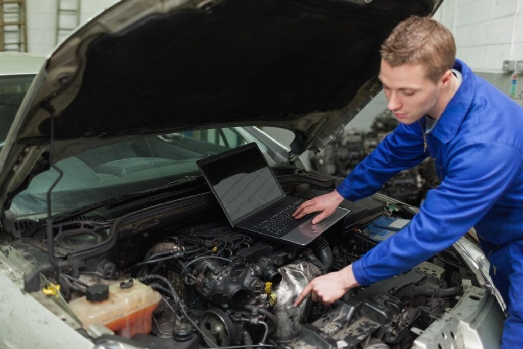 Wearing blue jumpsuit covered in grease, focused on repairing a car engine